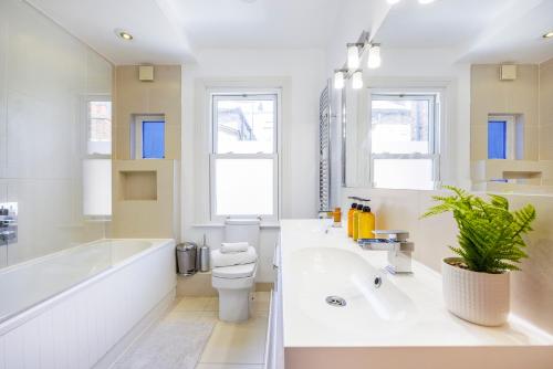 伦敦6 Bedroom House by AV Stays Acton Sleeps 11 Free Parking的白色的浴室设有浴缸、卫生间和水槽。
