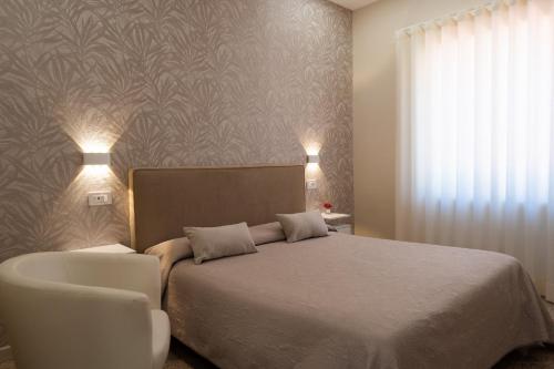 阿杰罗拉莱昂纳多住宿加早餐旅馆的一间卧室配有一张床和一张白色椅子