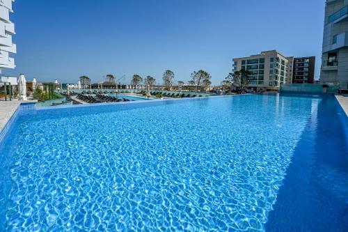 北马马亚-讷沃达里Aqua Vista Infinity Apartament Lux Vedere La Mare - Resort & Spa的一个大型蓝色游泳池,其建筑背景为: