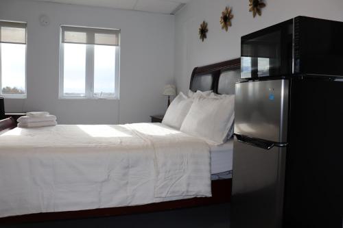圣热罗姆AMR Hotel Inc的卧室配有白色的床和冰箱。