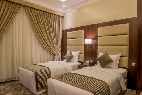 达曼نور الشرق的配有窗帘的酒店客房内的两张床