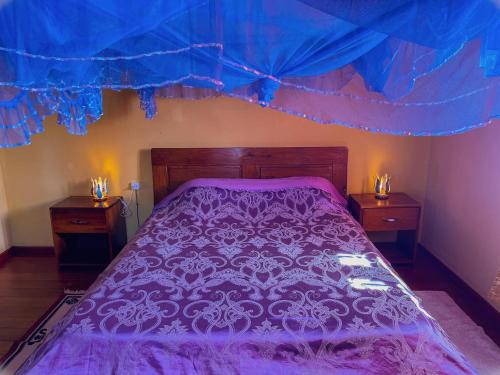 陶拉纳鲁Le Famanta - Hotel & Restaurant的一间卧室配有一张带2晚台的紫色床