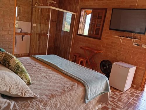 圣本图-杜萨普卡伊Chalés Bons Ventos - Chalé Estrela的一间卧室配有一张床和一台平面电视