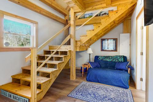布斯贝港Cooper Cottage的一个小房子里的一个螺旋楼梯,有蓝色的沙发