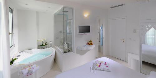 里乔内艾尔卡瓦利诺比安科酒店的白色的浴室设有浴缸和淋浴。