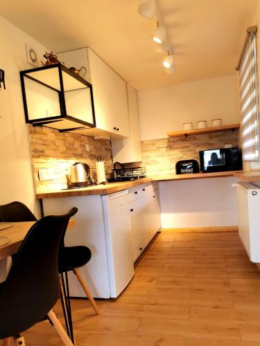 普热谢卡Chybotek Premium Domek Danusia的厨房配有白色橱柜、桌子和吊灯。