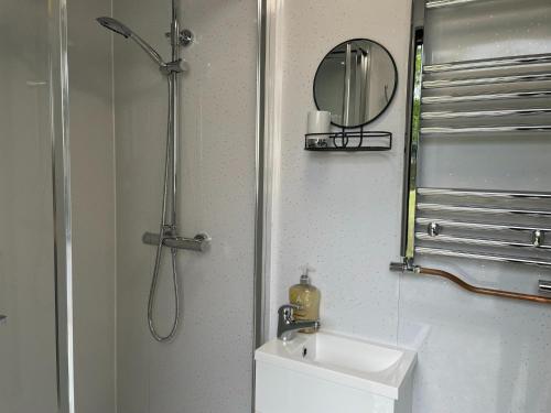 ToppesfieldWoodland Glamping Retreat的带淋浴、盥洗盆和镜子的浴室