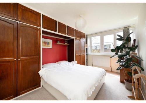 伦敦chic 3-BR home welll located in Islington的卧室配有白色的床和红色的墙壁