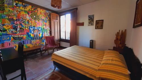 JuayúaHotel Anáhuac的卧室配有一张床,墙上挂有绘画作品