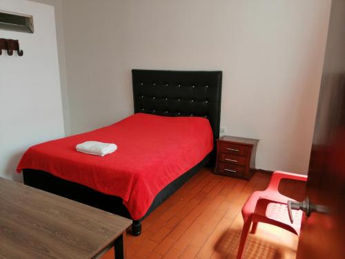 波帕扬Hotel El Carretero的一间卧室配有一张带红色毯子和桌子的床。