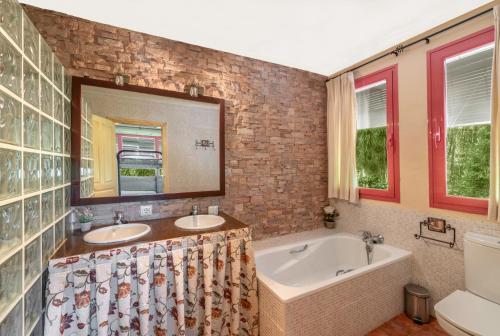 吉桑多El Bosque de la Herrezuela的浴室设有2个水槽、浴缸和镜子