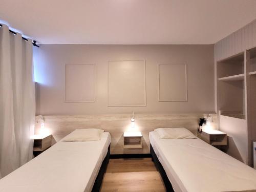 巴西利亚伊科诺酒店的两张床位于带两盏灯的墙上。