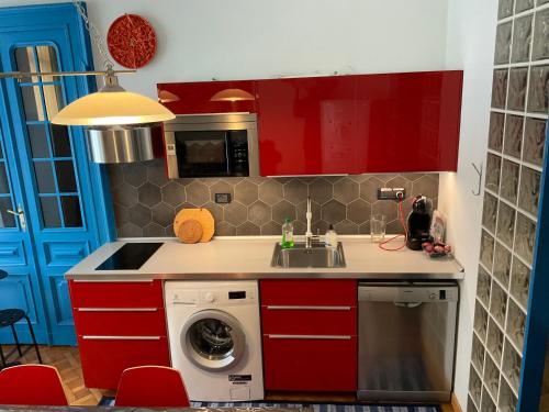 都灵NONPERTUTTI PIAZZA CASTELLO Senior e famiglie TOP的一间带红色橱柜和洗衣机的厨房