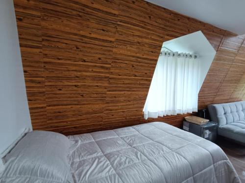 MuyurinaVallecito Lodge的卧室设有木墙、一张床和椅子