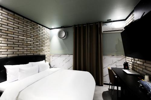 首尔Stay 25 Hotel的卧室配有白色的床和砖墙