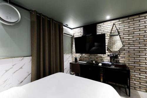 首尔Stay 25 Hotel的卧室配有1张床和1台砖墙电视