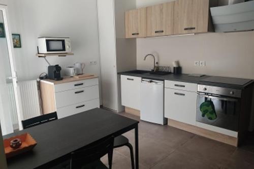 莱斯安格尔斯Cozy studio near Avignon的厨房配有白色橱柜和黑色台面