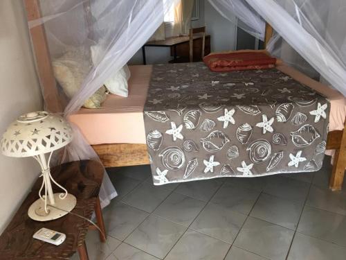 Palmarinla villa sur la plage的一间卧室配有一张床和一张带台灯的桌子