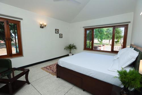 BahoraDe Vivendi Farm- A Rural Luxury Farmhouse Getaway的一间卧室设有一张大床和两个窗户。