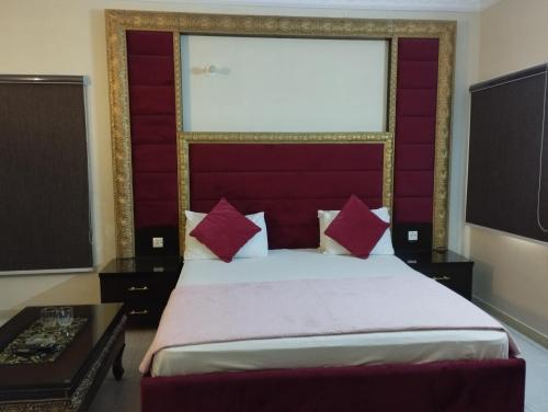 卡拉奇Hotel Shelton的一间卧室配有一张大床和红色床头板