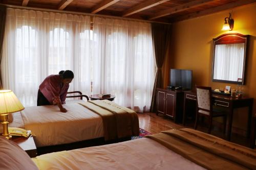 帕罗Tiger's Nest Resort - Best Resort In Paro的一位女性在旅馆房间做床