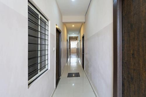 科塔OYO HOTEL SHRI KALYAN的一条带白色墙壁的走廊和一个带窗户的长走廊