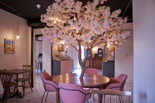 里摩日Théo Hôtel Limoges, The Originals City的一间设有桌子的用餐室和一棵带粉红色花卉的树