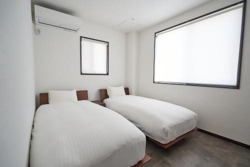 富士河口湖08 Resort Club -Theater-的白色客房的两张床,设有两扇窗户