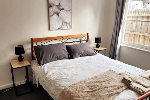 墨尔本Charming Home Near Melbourne Airport & CBD的一间卧室配有一张带两张台灯的床铺。