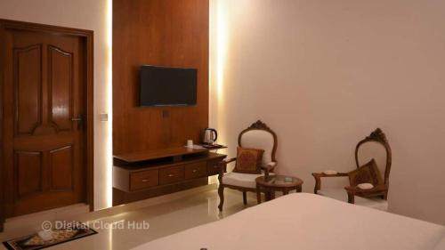 卡拉奇Ambassador Hotel Clifton的一间卧室配有一张床、一张书桌和一台电视