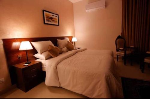 卡拉奇Ambassador Hotel Clifton的一间卧室配有一张大床、两盏灯和一把椅子