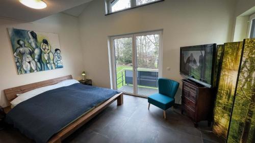 StipshausenANDERSWELTENlodge的一间卧室配有一张床、一台电视和一把椅子