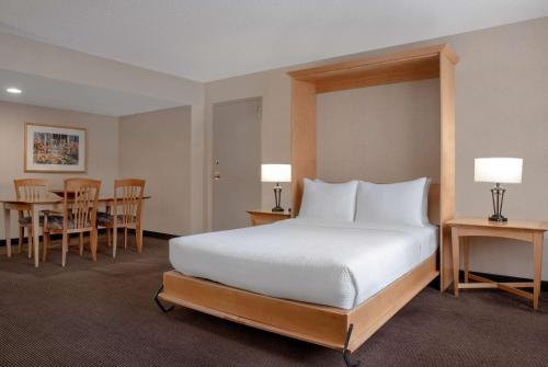 卡尔加里卡尔加里市中心华美达酒店的卧室配有一张床和一张桌子及椅子