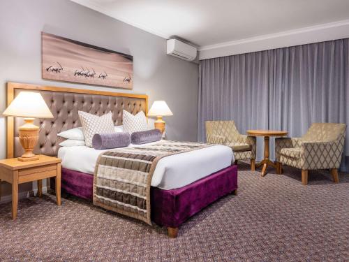 温特和克Mercure Hotel Windhoek的酒店客房带一张大床和一把椅子
