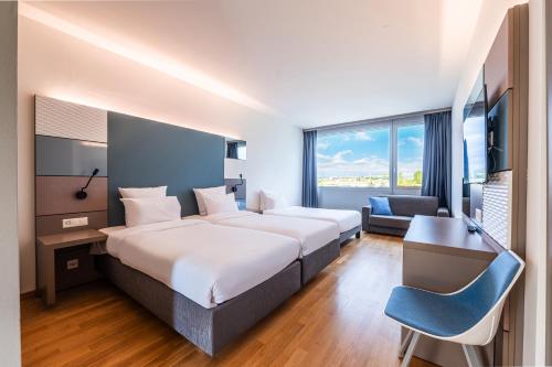 洛桑B&B HOTEL Lausanne Crissier的酒店客房配有两张床和一张书桌