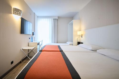 圣安德烈斯-德拉巴尔卡加泰罗尼亚布里斯托尔酒店的酒店客房带两张床,有橙色和白色的地毯。