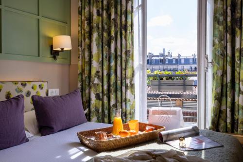 巴黎克莱门特酒店的酒店客房在带窗户的床上提供橙子托盘
