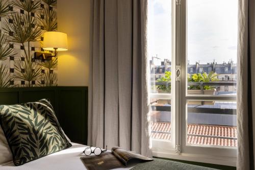 巴黎克莱门特酒店的一间卧室设有一张床和一个大窗户