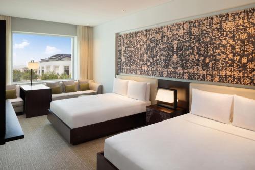 马斯喀特JW Marriott Hotel Muscat的酒店客房,设有两张床和一张沙发