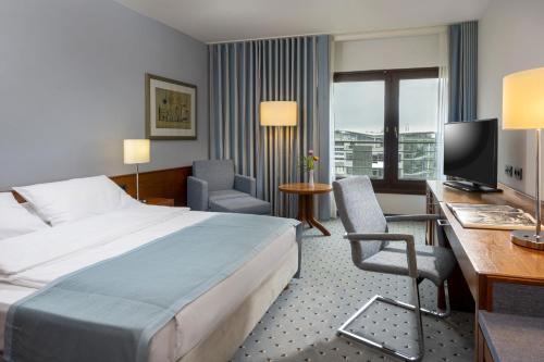 达姆施塔特达姆施塔特马里提姆酒店的酒店客房配有一张床、一张书桌和一台电视。