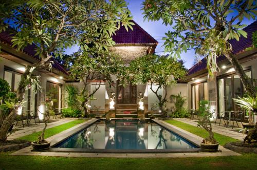 沙努尔信德梅特套房酒店的享有带游泳池和树木的别墅的外部景色