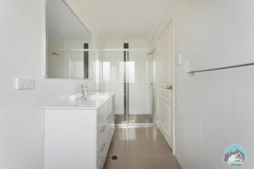 悉尼Aircabin - Telopea - Sydney - 5 Beds Holiday House的带淋浴和盥洗盆的白色浴室