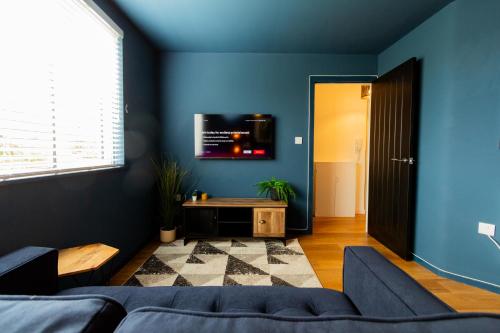 威根Wigan Gem: Chic 1BR close to CC的蓝色的房间,配有沙发和墙上的电视