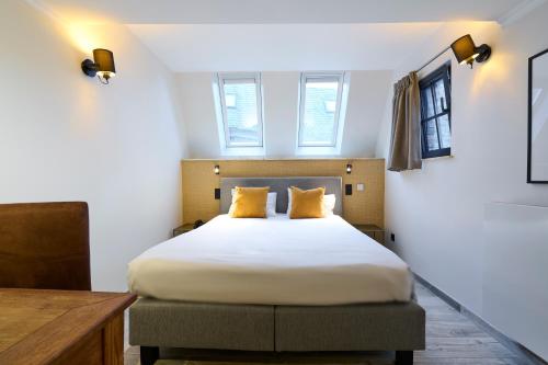 那慕尔莱斯坦努斯酒店的一间卧室配有一张带黄色枕头的大床