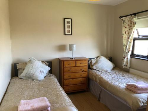 斯皮德尔Spiddal Cottage的一间卧室设有两张床、一个梳妆台和窗户。