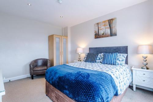 Barnetby le Wold何尔康宾馆的一间卧室配有一张带蓝色被子和椅子的床