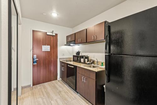 奇珀瓦福尔斯Riverstone Suites by Cobblestone Hotels - Chippewa Falls的厨房配有黑色冰箱和木制橱柜。