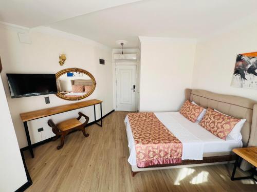 ErdemliRoxo Beach Hotel的一间卧室配有一张床、镜子和一张书桌