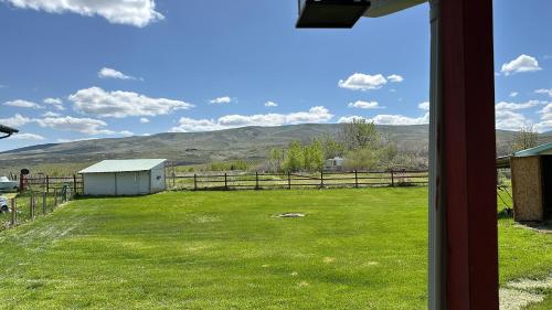 NachesInfidel Acres Motorcycle tent spaces.的从带栅栏和山脉的田野窗户欣赏美景