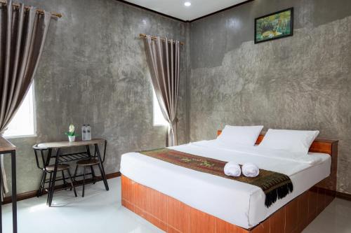 Buengngarm Resort的一间卧室配有一张大床和一张桌子